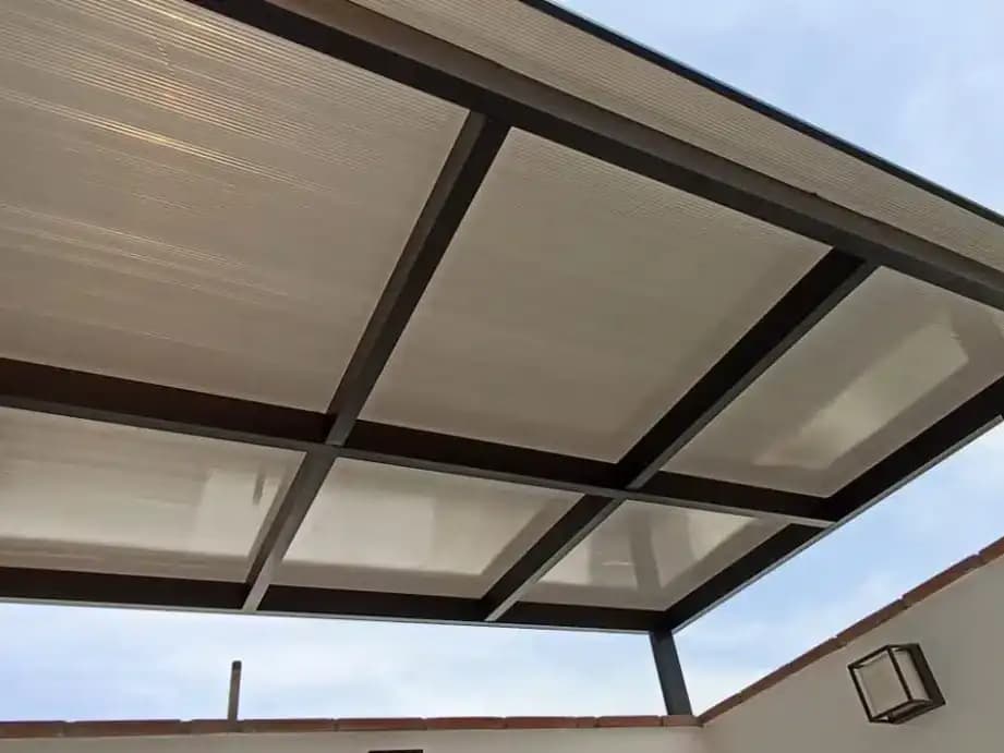 Cobertura de policarbonato sobre una estructura metálica en una azotea, vista desde abajo